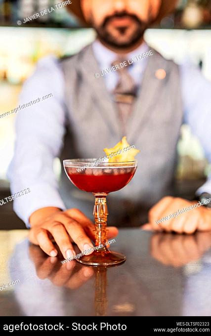 Male bartender serving cocktail at bar counter
