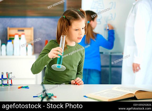 Elementary age school girl looking at test tube in science class at primary school