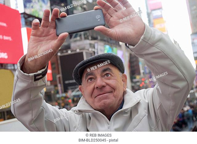 Hispanic man posing for cell phone selfie in city