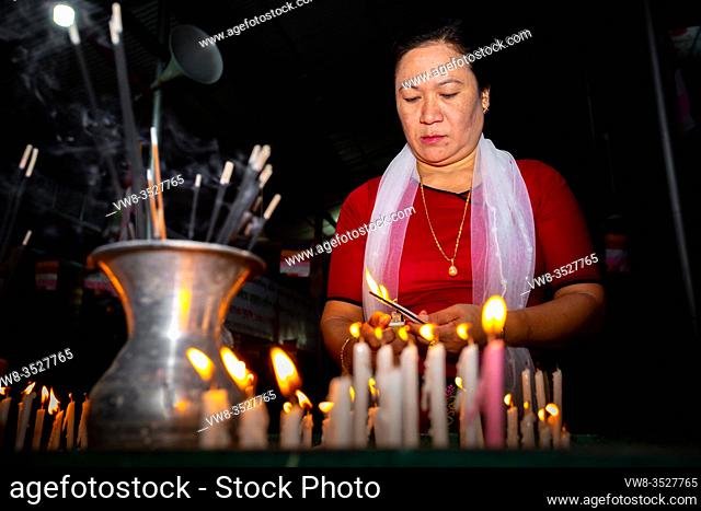 Bangladesh - October 13, 2019: A Buddhist woman is lighting candles in the Ujani Para Buddhist Temple at Bandarban, Bangladesh