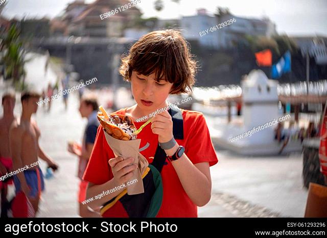 A teenager eats a bubble waffle on the promenade of Puerto de la Cruz. Tenerife. Canary Islands. Spain