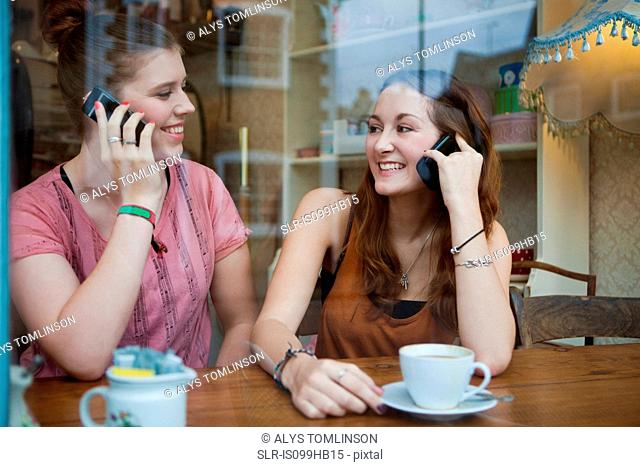 Young women in cafe on cell phones