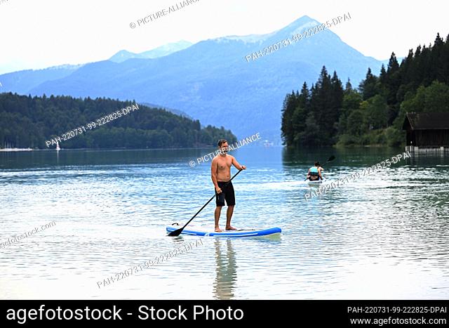 31 July 2022, Bavaria, Niedernach: Stand-up paddler Moritz Müller rides his board in Lake Walchen. Photo: Felix Hörhager/dpa