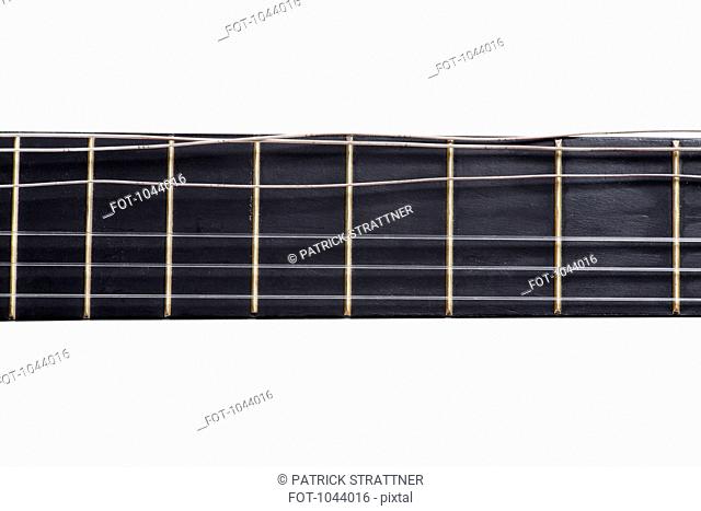 An acoustic guitar fretboard with a damaged string, close-up