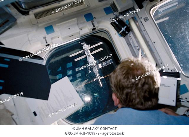Astronaut Andrew S.W. Thomas looks through one of the windows on the aft flight deck of the Space Shuttle Discovery as it approaches the International Space...