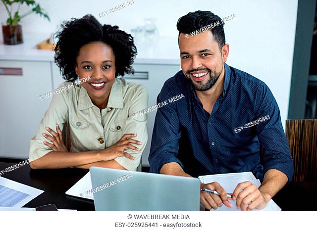 Portrait of smiling two business executives working on laptop