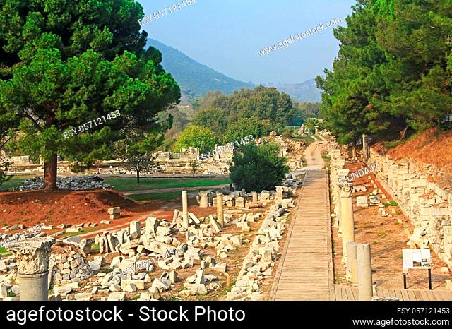 Scenic view of mountains and marble columns beside a wooden walkway along the Commercial Agora in the ancient city ruins of Ephesus