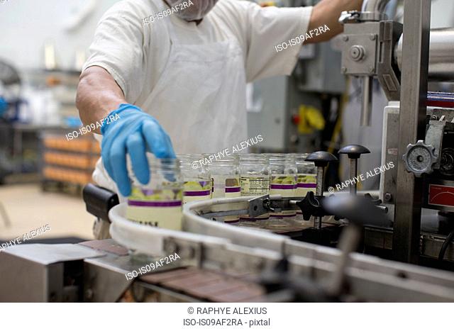 Man handling glass jars on production line