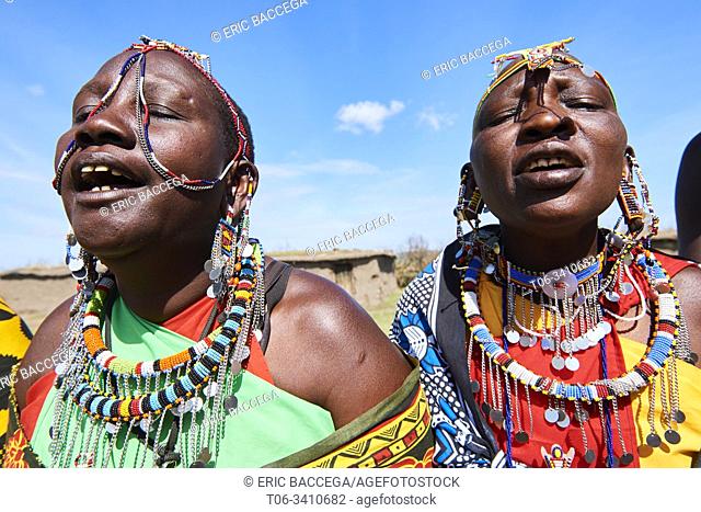 Group of Massai women singing and dancing in traditional dress and adorned with bead work, Masai Mara National Reserve, Kenya