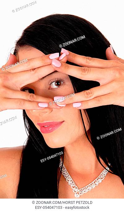 A beautiful woman in close up holding her hands over her face and looking trough the fingers, isolated for white background