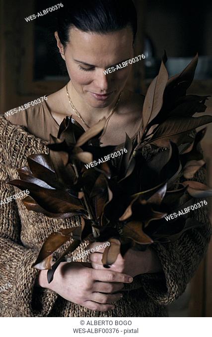Woman with bunch of twigs with brown leaves