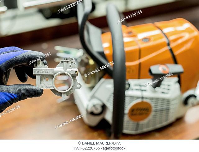 An employee of chainsaw producer Stihl shows a pump to put sticking oil onto the chain of a chainsaw in Waiblingen, Germany, 24 September 2014