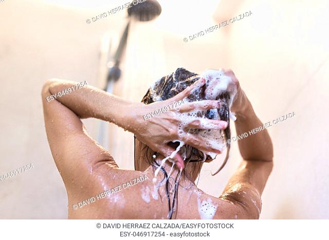 Young woman washing hair in shower. Beauty concept