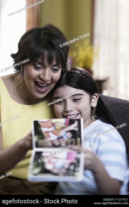 Hispanic mother and daughter looking at photo album