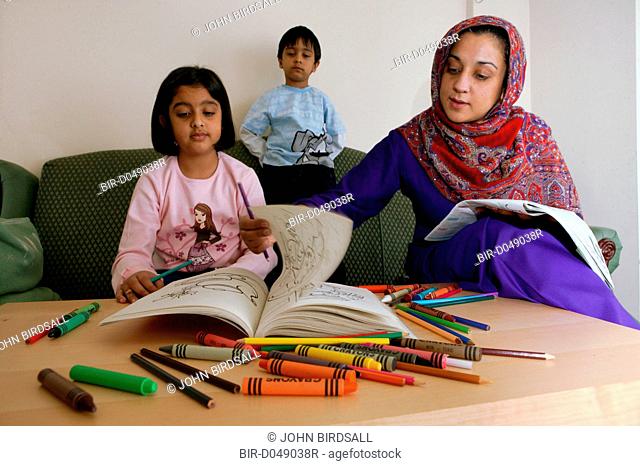 Single parent helping her young children with colouring book