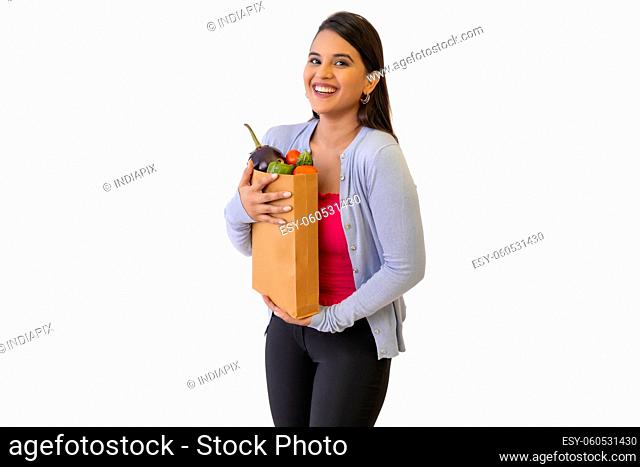 Indian lady holding a bags full of vegetables