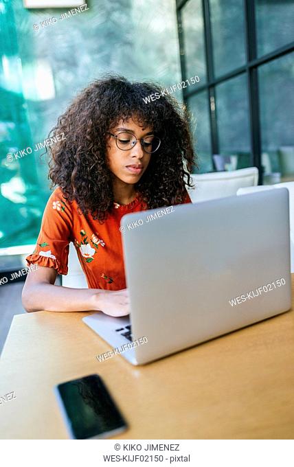 Portrait of serious young woman using laptop in a coffee shop
