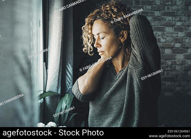 Young mature woman touching his neck for backpain and stretching arms. Concept of healthy and body condition people Female massaging his back for pain and...