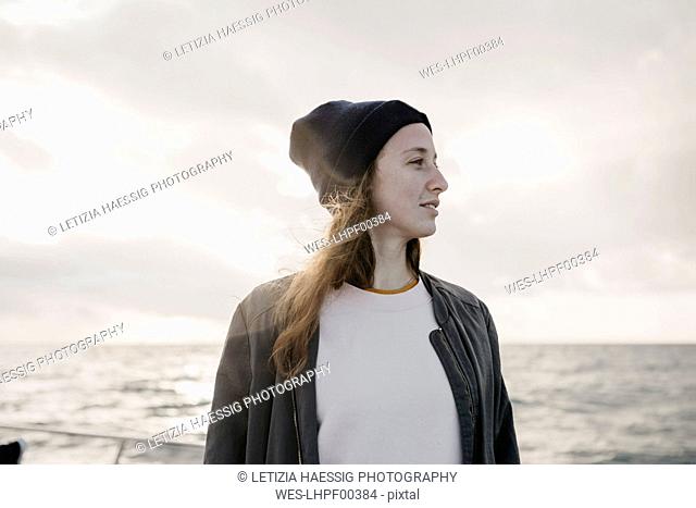 South Africa, young woman with woolly hat during boat trip at sunset
