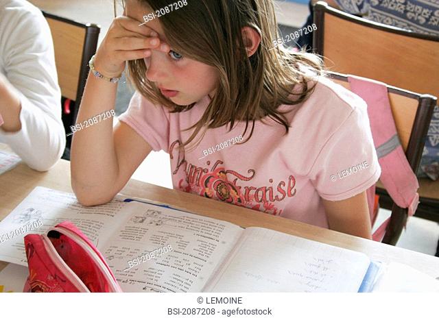 SCHOOLCHILD Schoolgirl in 1st grade doing reading homework in class