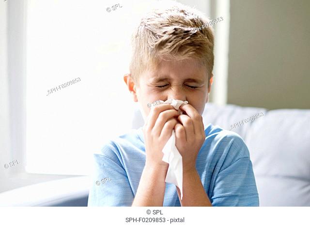 Young boy blowing his nose on a tissue