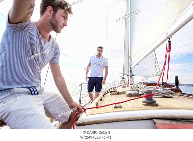 Young man pulling rope on sailboat
