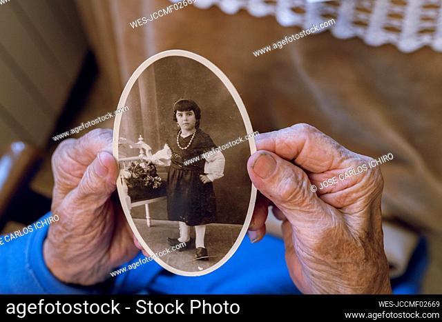 Senior woman with childhood photograph at home