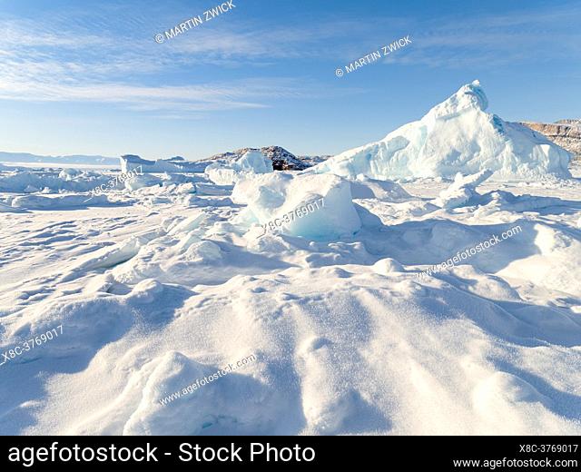 Icebergs in front of Appat Island, frozen into the sea ice of the Uummannaq fjord system during winter in the the north west of Greenland