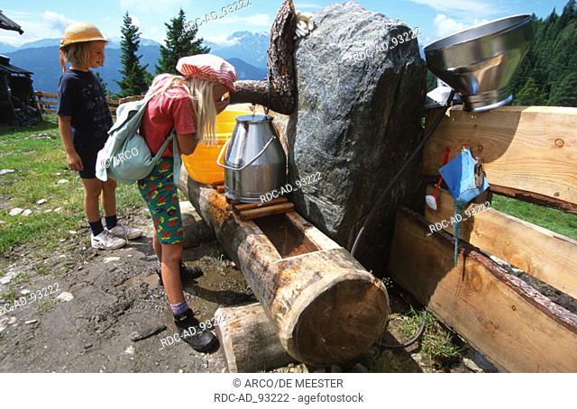 Girls drinking from fountain at mountain hut Irschen Carinthia Austria alps