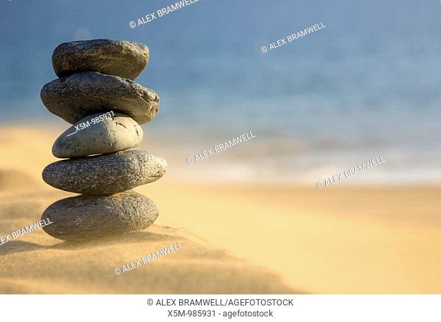 Stack of volcanic pebbles on a beach with blowing sand