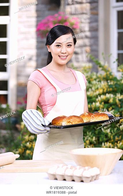 Oriental woman baked bread in the outdoor kitchen