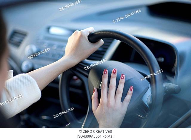 Cropped view of young businesswoman's hands pressing car horn