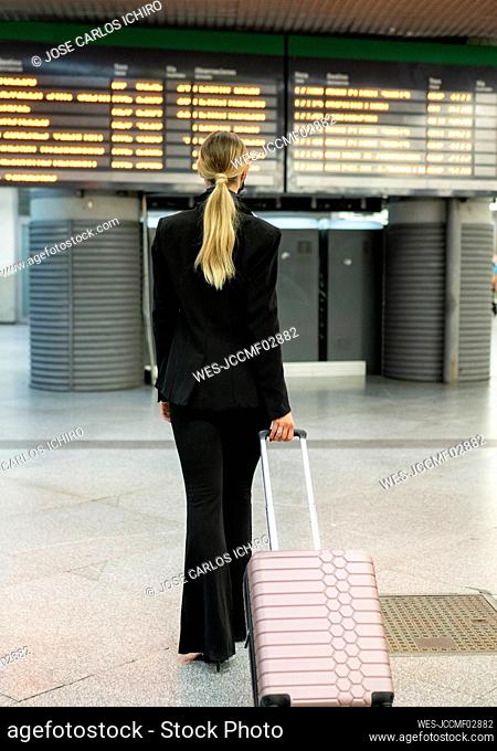 Female flight attendant walking with suitcase at airport