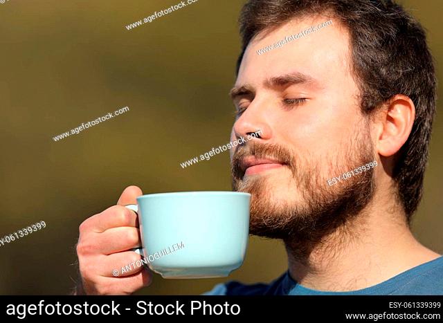 Close up portrait of a man smelling coffee aroma outdoors