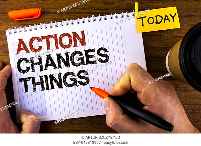 Text sign showing Action Changes Things. Conceptual photo doing something is like chain Improve Reflects written by Man Notepad holding Marker Wooden background...