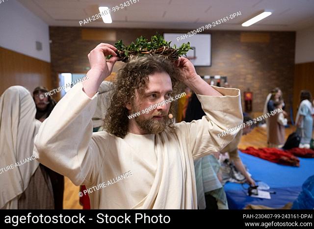 07 April 2023, Hesse, Bensheim: Jesus actor Julian Lux tries on the crown of thorns before the Good Friday procession. Around 90 amateur actors and actresses in...