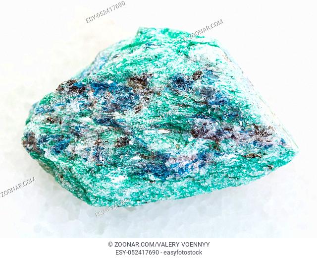 macro shooting of natural mineral rock specimen - rough Fuchsite (chrome mica) stone on white marble background from Hizovaara, Republic of Karelia in Russia