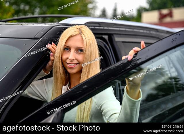 Close up portrait of a smiling young woman looking out of car window and enjoying the view