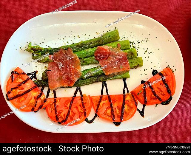 Grilled green asparagus with ham and tomato salad. Spain