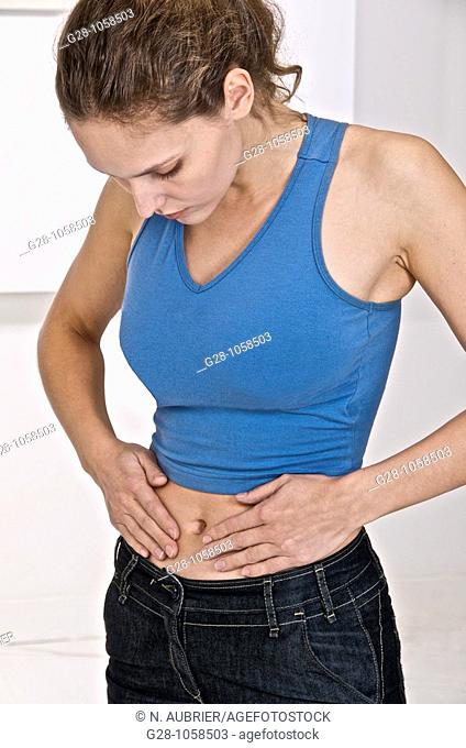 young woman holding her stomach and suffering from periods or stomach pains