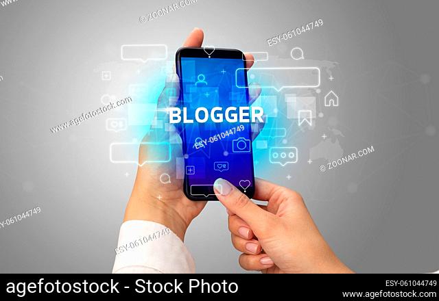 Female hand typing on smartphone with BLOGGER inscription, social media concept