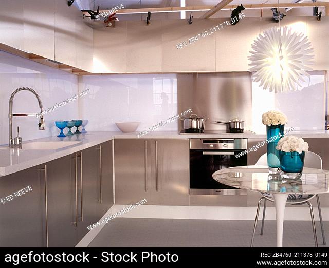 A modern minimalist kitchen with dining area stainless steel unit round breakfast table hanging light