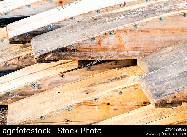 Wooden rafting boats on a pile on the river bank - stored in parts