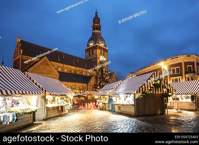 Riga, Latvia. Christmas Market On Dome Square With Riga Dome Cathedral. Christmas Tree And Trading Houses. Famous Landmark At Winter Xmas Evening Night In...