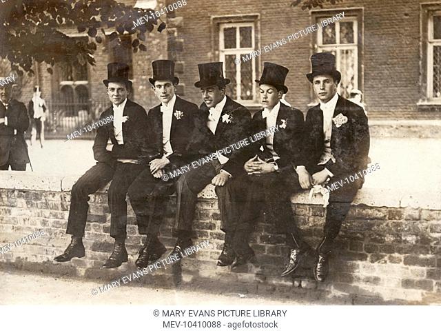 Five Eton schoolboys in smart suits and top hats, sitting on a wall on 4 June, traditionally the date when King George III's birthday is celebrated at the...