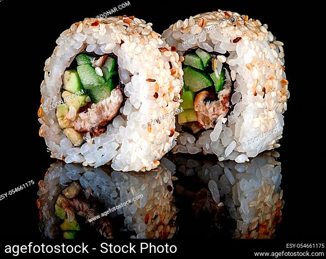 Closeup two sushi roll california on black background. Sushi roll with eel, vegetables and unagi sauce. Reflection