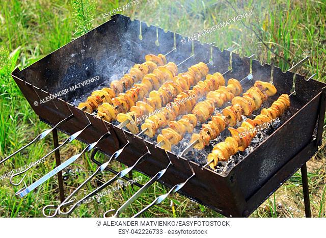 Shashliks from pieces of potatoes and bacon. Cooking of potatoes and bacon on fire. Picnic at nature. Barbecue lunch. Marinated shashlik from potatoes and bacon...
