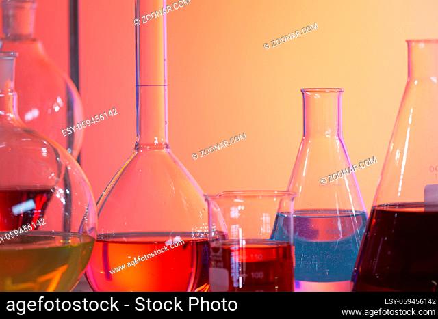 Backlit laboratory test flask containing colorful liquids. Concept of chemistry and research