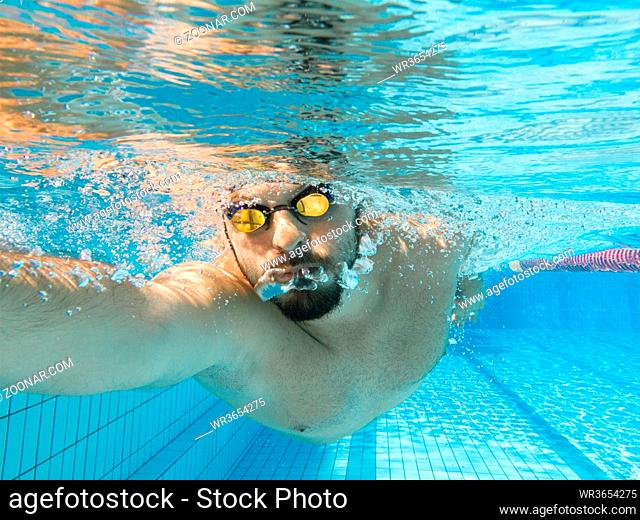 Young male athlete swimming freestyle crawl under water view