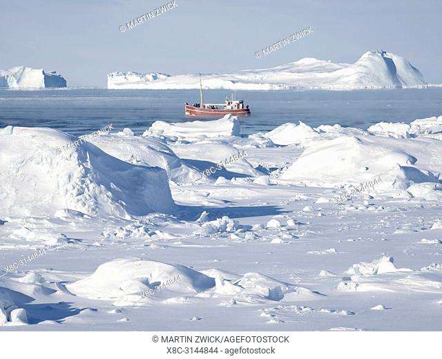 Boat on the frozen Disko Bay with icebergs at the Ilulissat Icefjord . The icefjord is listed as UNESCO world heritage. America, North America, Greenland